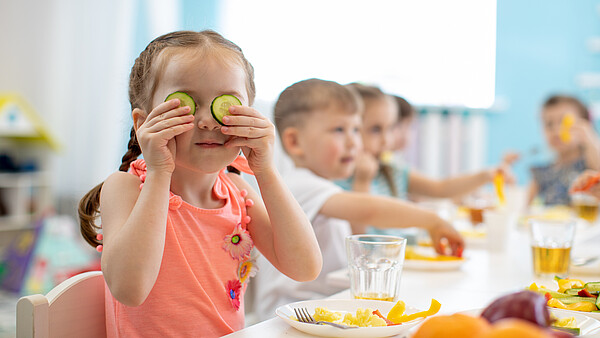 Fröhliches Kind bei einer gesunden Mahlzeit im Kindergarten / in der Kindertagesstätte