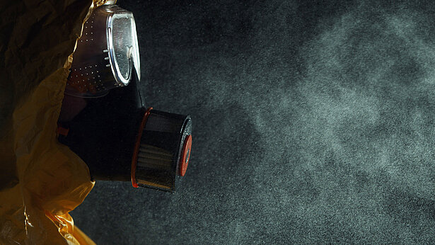 Mann im Schutzanzug mit Atemschutzmaske und Schutzbrille