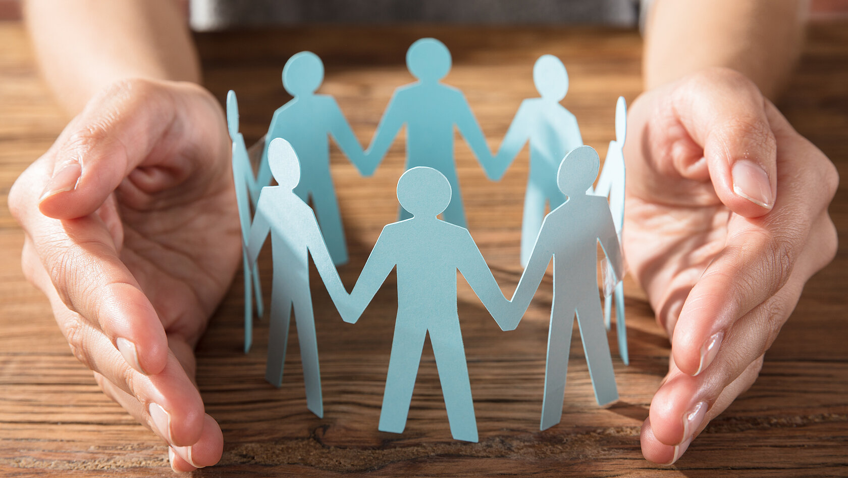 Hände schützen ausgeschnittene Papierfiguren