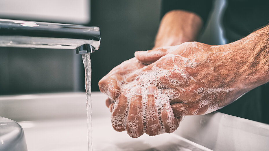 Mann wäscht sich die Hände am Waschbecken unter fließendem Wasser