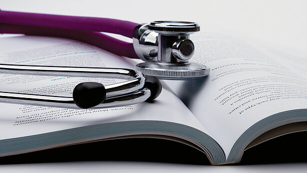 Stethoskop liegt auf einem aufgeschlagenen Buch