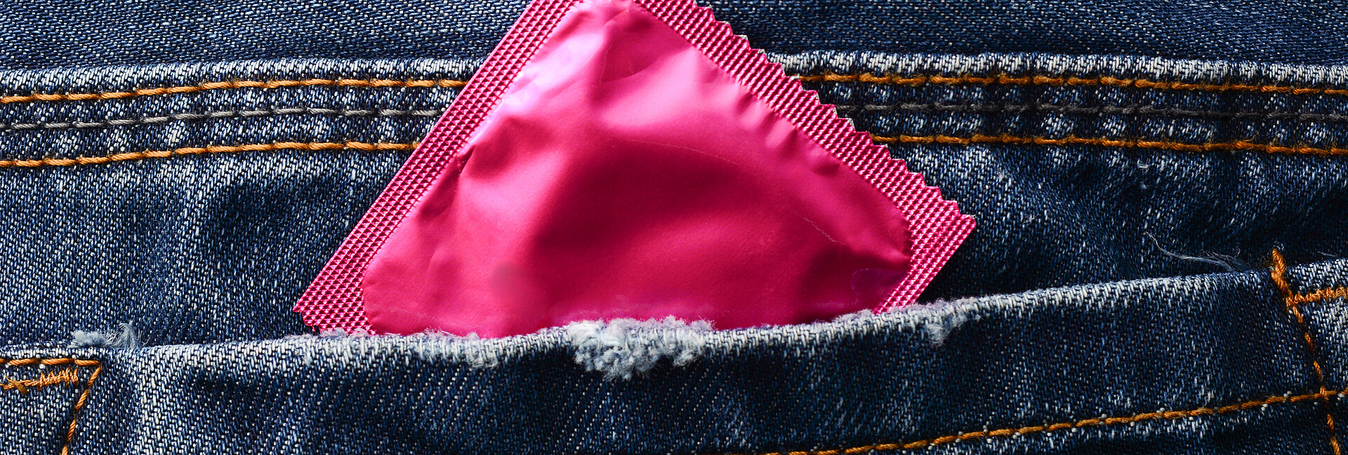 Rosafarbene Kondompackung in einer Hosentasche