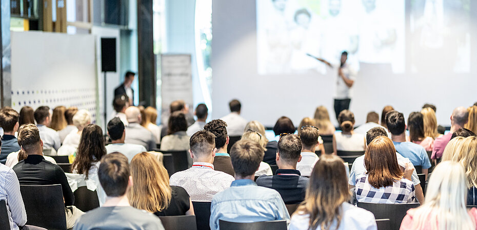 Sprecher hält einen Vortrag vor Publikumbei einer Veranstaltung im Saal