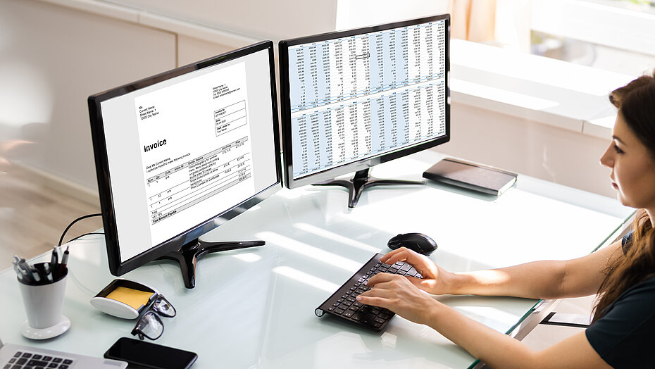 Eine Frau schreibt am Computer, vor sich zwei Bildschirme