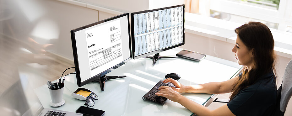 Eine Frau schreibt am Computer, vor sich zwei Bildschirme