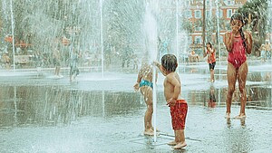 Kinder plantschen in einem Brunnen in der Stadt