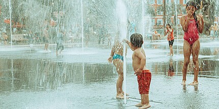 Kinder plantschen in einem Brunnen in der Stadt