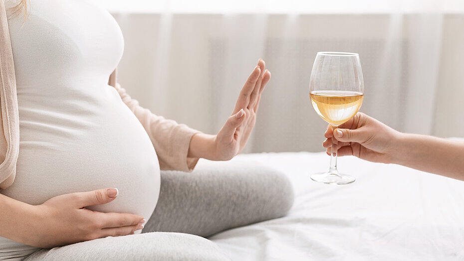 Schwangere Frau lehnt ein Glas Alkohol ab