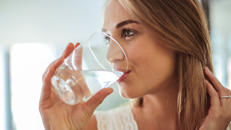 Junge Frau trinkt ein Glas Wasser