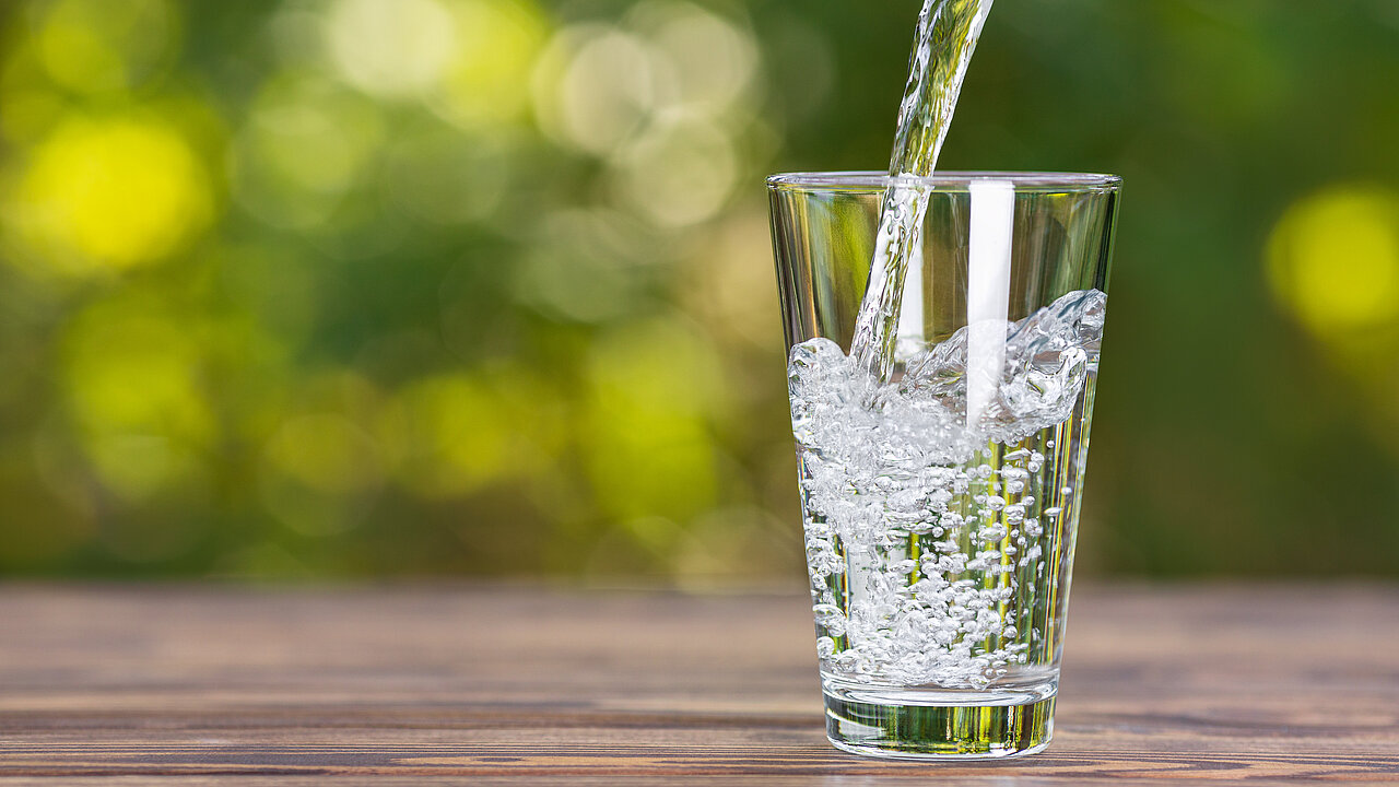 Wasserstrahl fließt in ein Trinkglas