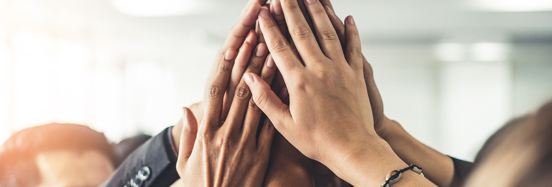 Zufriedene Geschäftsleute heben zusammen die Hände