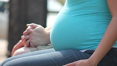 Schwangere Frau hält Händchen mit ihrem Partne
